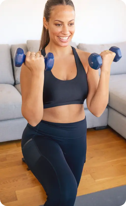 Smiling women exercising with dumbbells in her living room